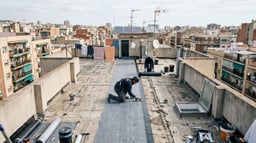 Azotea comunitaria plana de un edificio residencial español durante la impermeabilización con membrana, mostrando petos, sumideros y uso comunitario