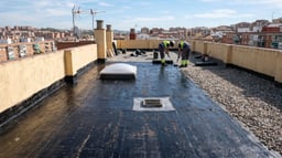 Azotea de un edificio residencial en proceso de impermeabilización, con membrana aplicada, peto perimetral, sumidero y lucernario visibles.